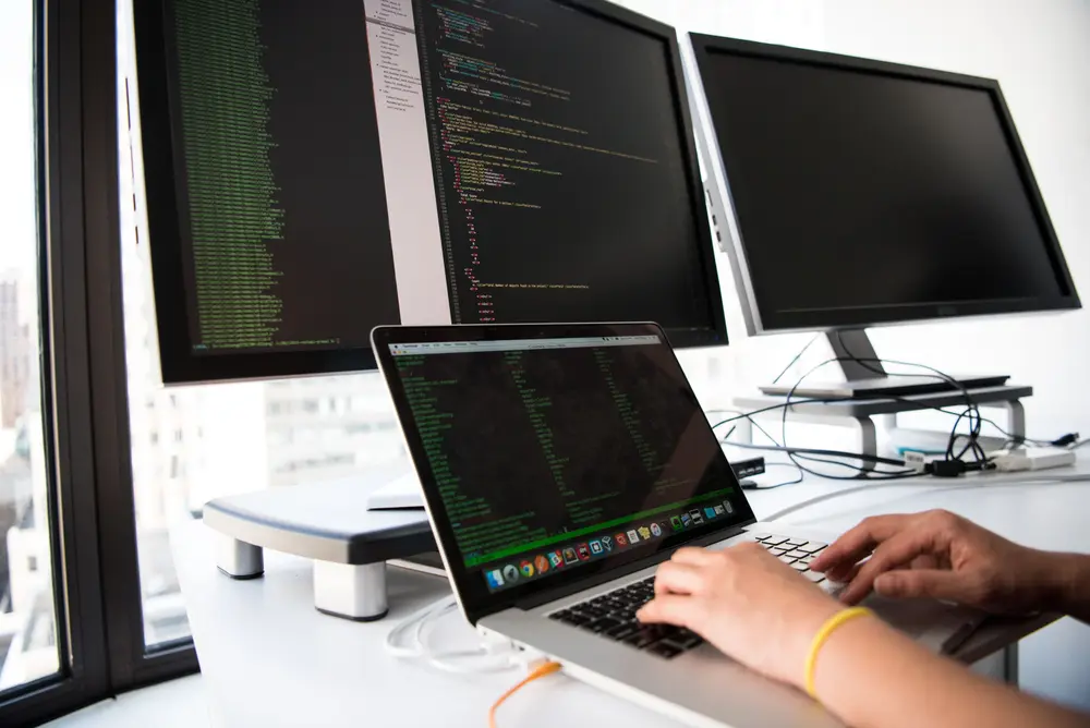 Développeur qui écrit du code devant plusieurs écrans